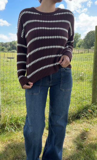 Brown and white striped ribbed sweater paired with high-rise blue jeans in a relaxed outdoor fall look.